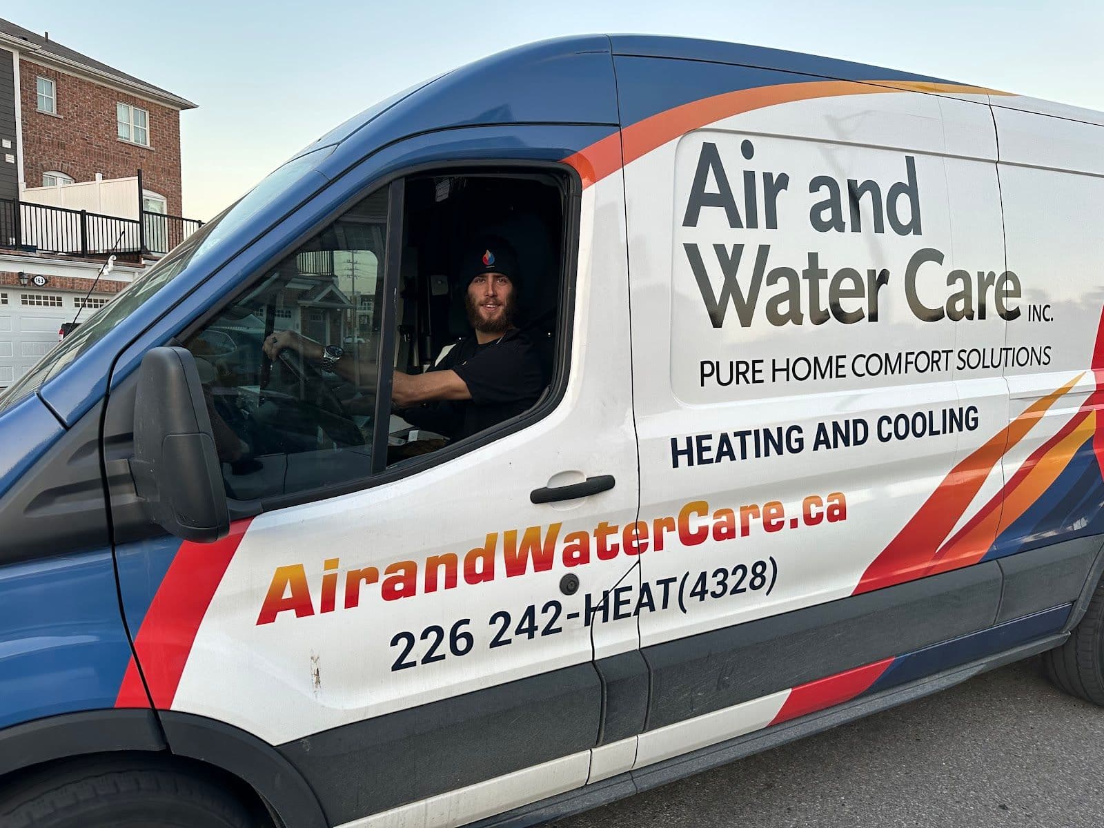 A home services technician and office manager reviewing customer feedback together on a tablet inside a work van parked outside a residential property