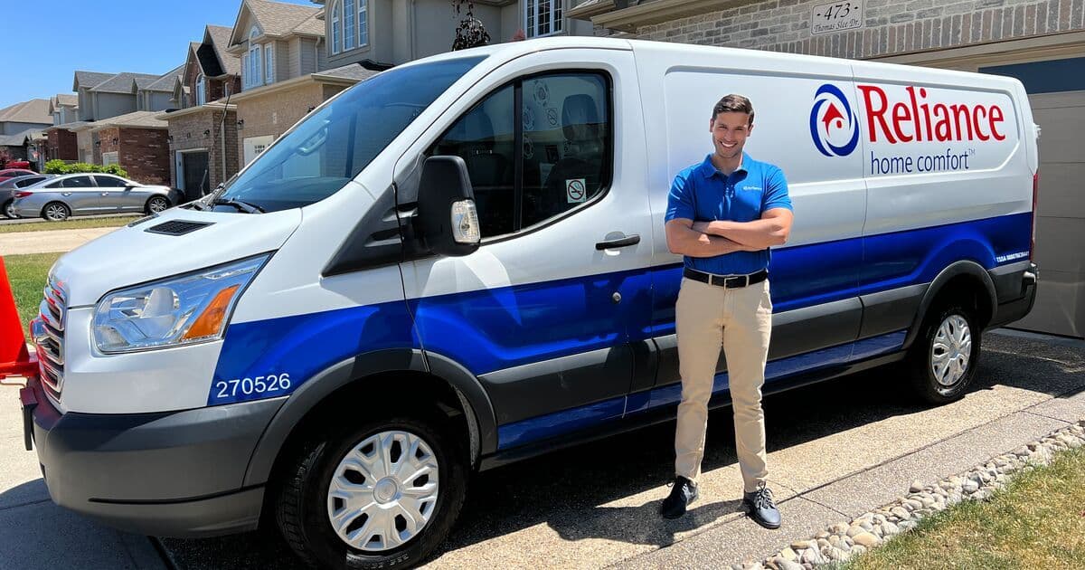Two home comfort technicians in a service van reviewing customer feedback and recent Google reviews on a tablet after completing a furnace and water heater installation