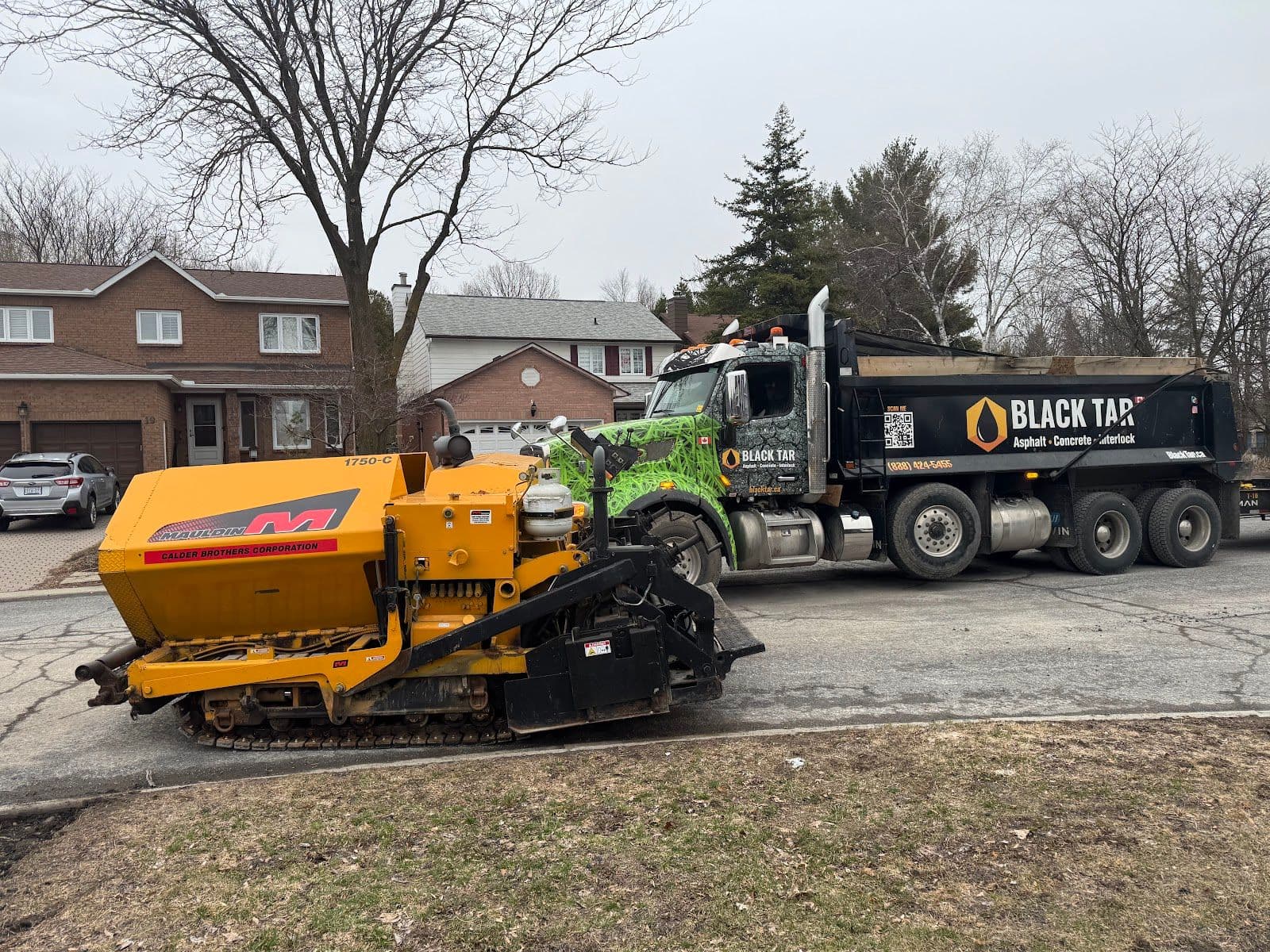 A paving crew reviewing customer feedback on a tablet beside their work truck after completing a driveway job