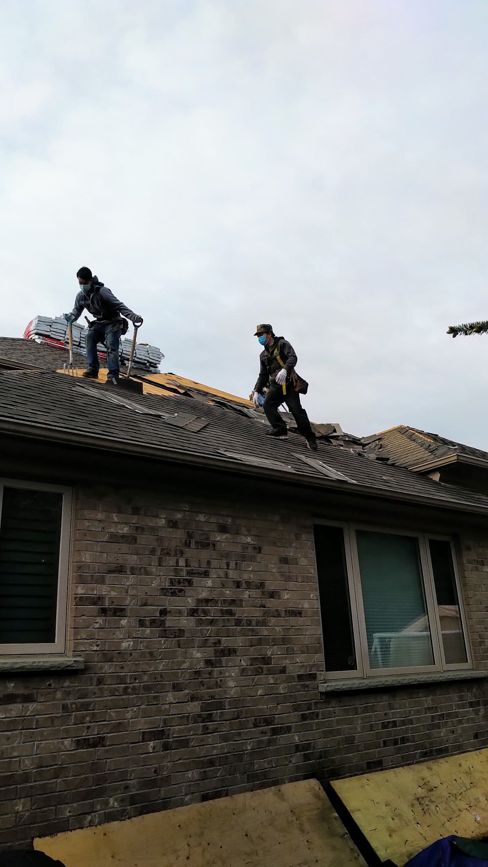A roofing crew reviewing customer feedback together on a tablet while standing beside their work van on a residential street