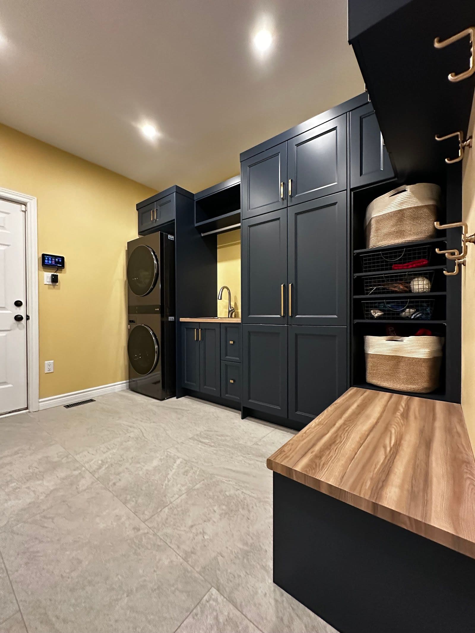 A home renovation crew reviewing customer feedback together on a tablet while standing in a freshly finished basement, tools and materials visible in the background