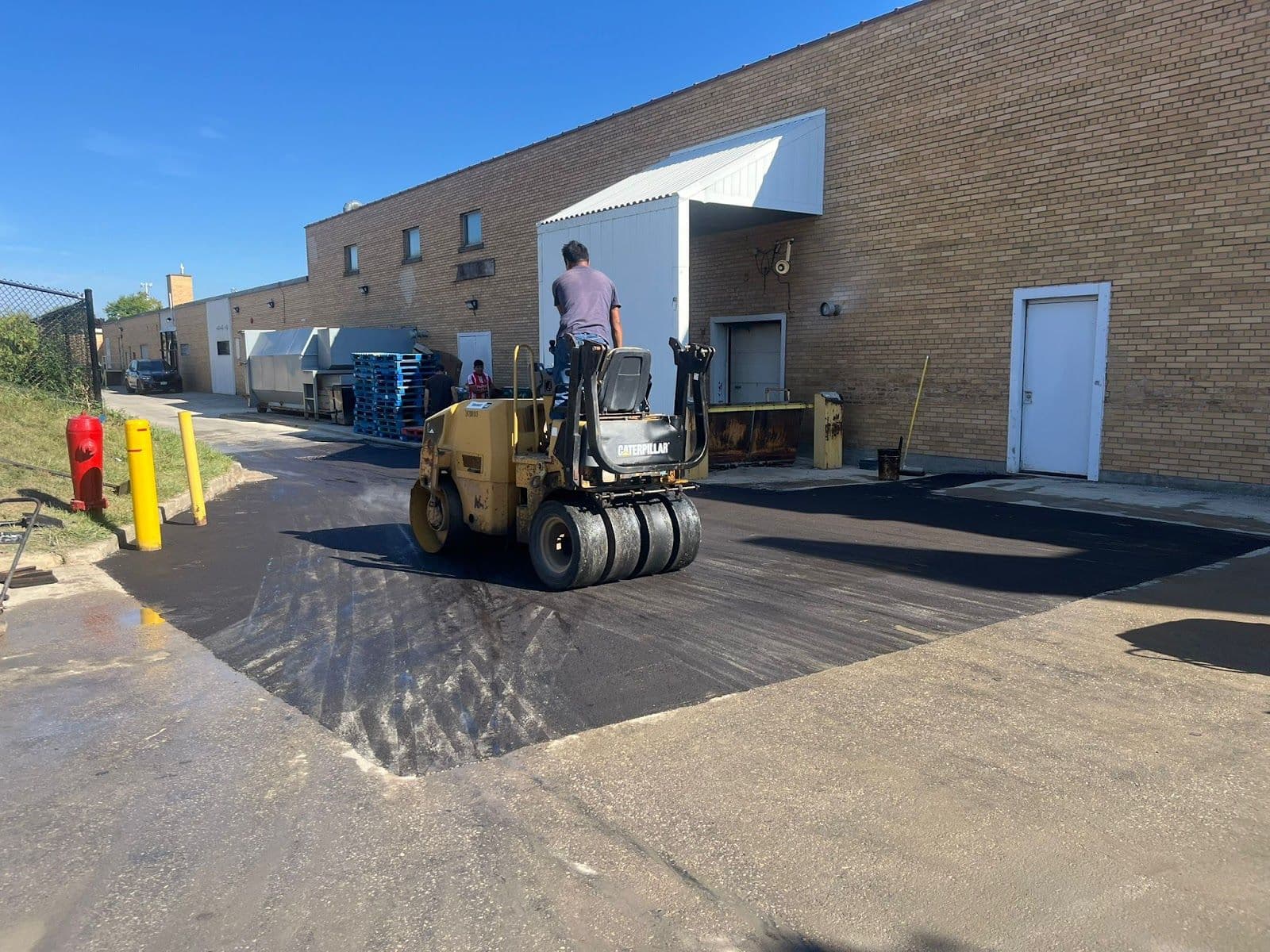 A paving crew leader and office manager reviewing customer feedback together on a tablet while standing beside a work van at a residential job site.