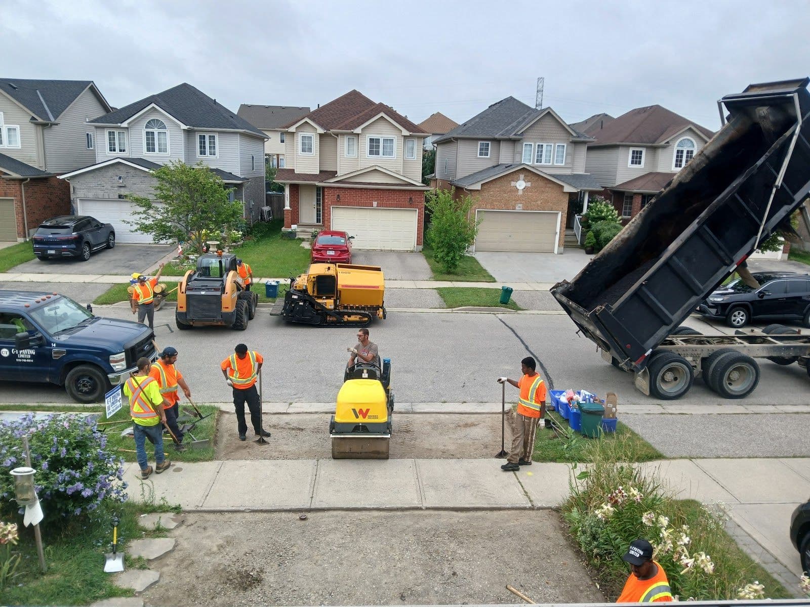 A paving crew in a work truck reviewing customer feedback on a tablet at a completed residential driveway job site