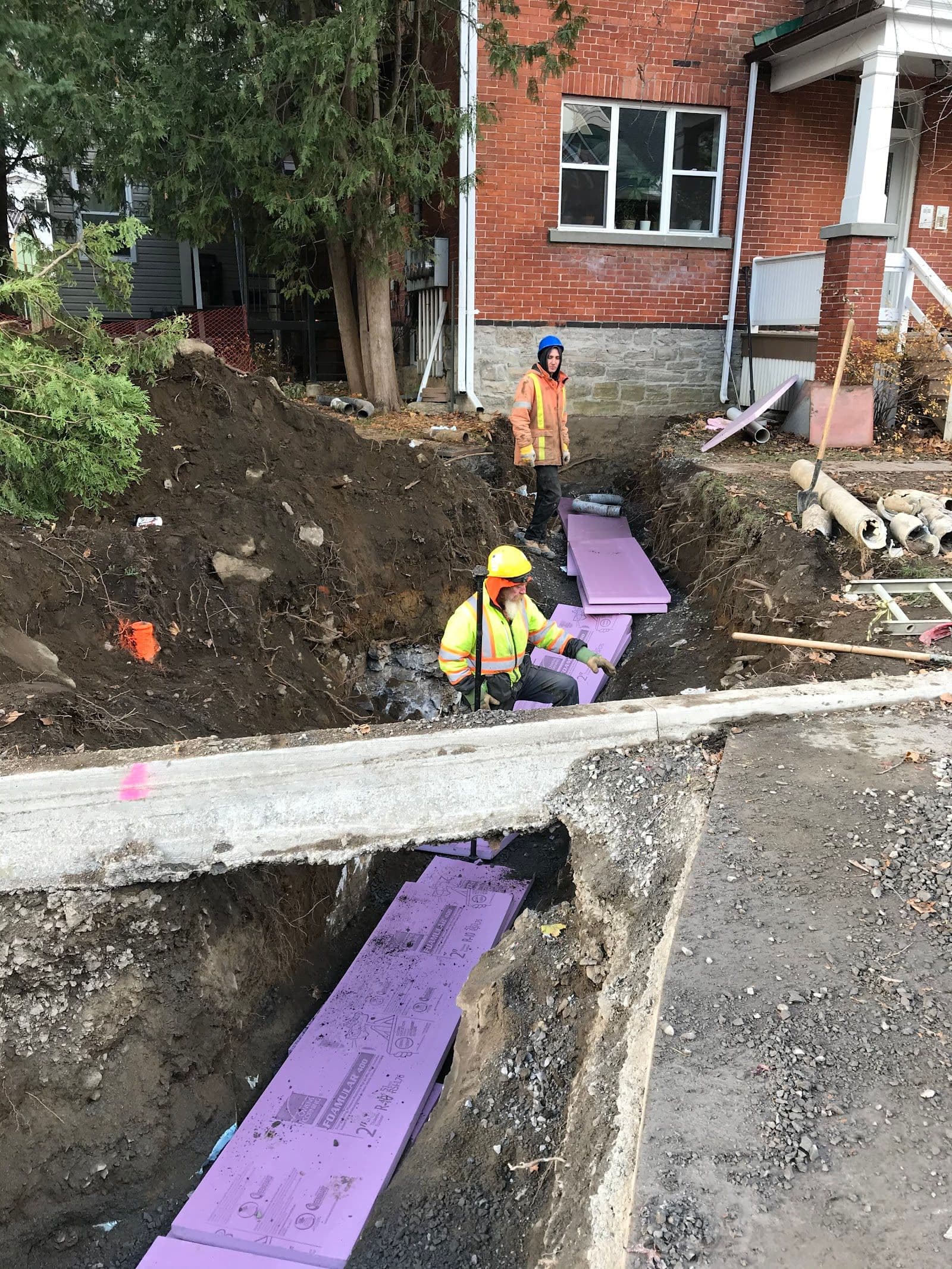 A construction crew foreman and office manager reviewing customer feedback together on a tablet beside a work van at a residential job site
