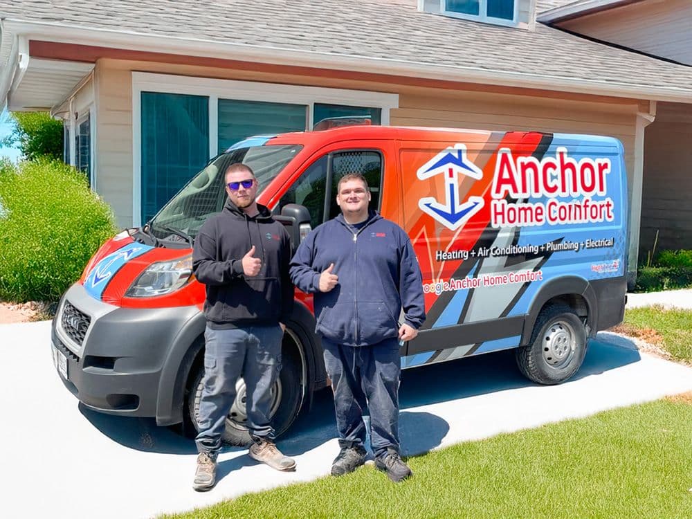 A home comfort technician and office manager reviewing customer feedback on a tablet while sitting in a service van outside a residential home