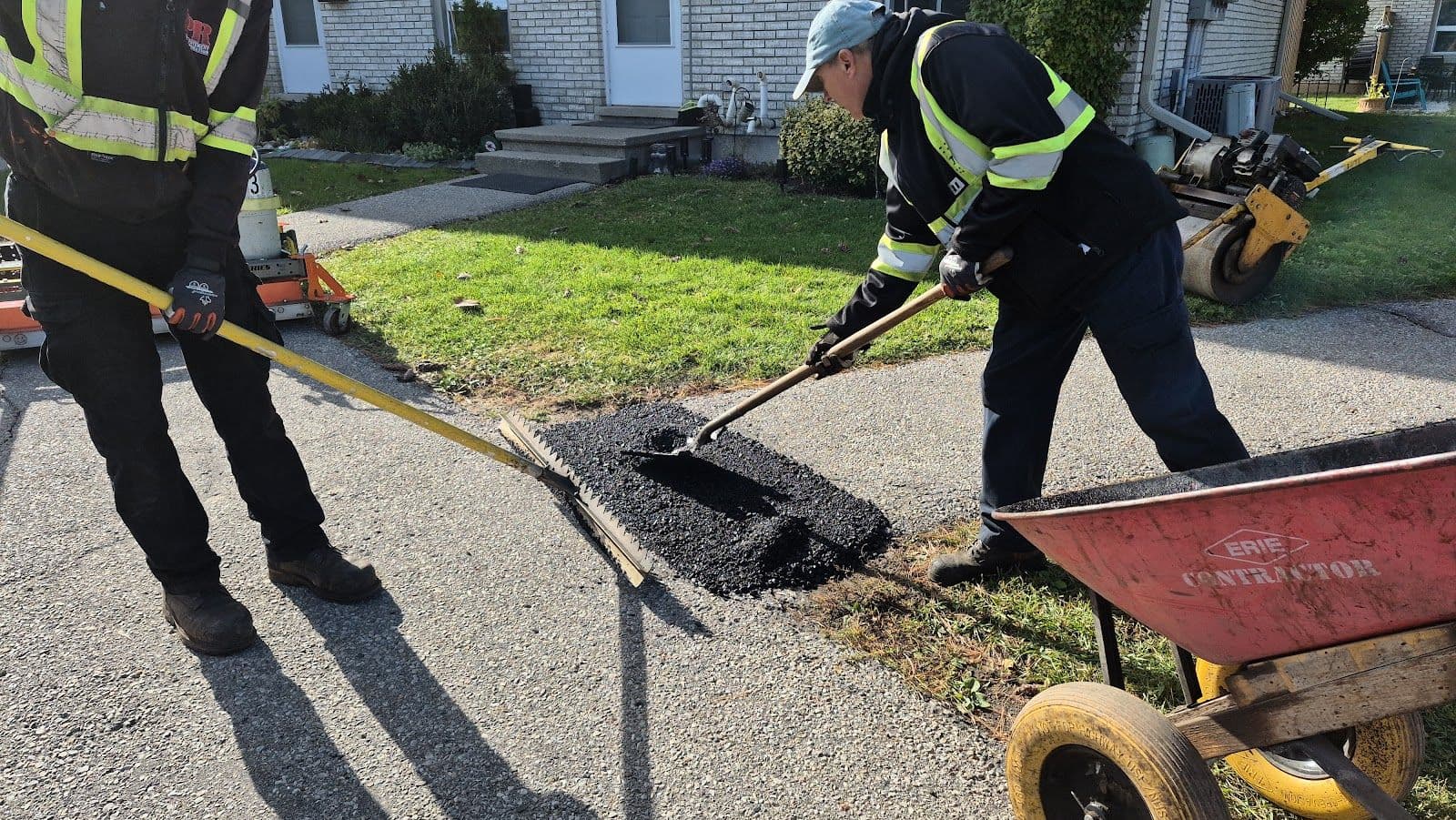 Two pavement repair crew members reviewing customer feedback on a tablet while standing beside their work truck at a job site