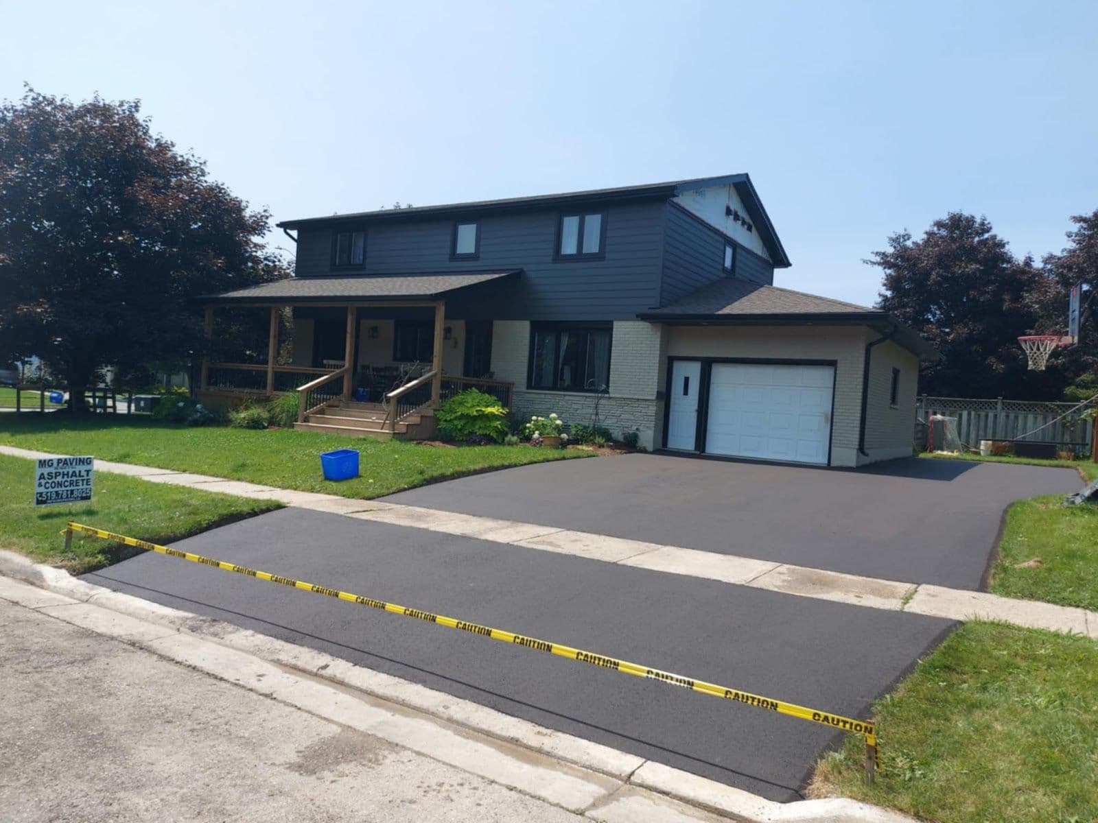 A paving crew reviewing customer feedback together on a tablet while standing beside their work truck at a freshly paved residential driveway