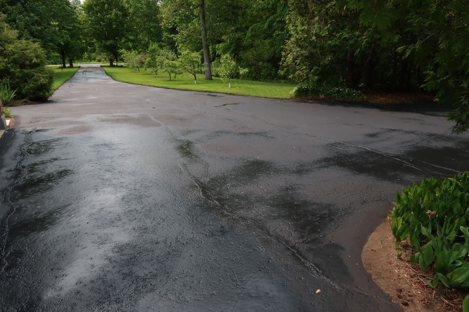 Asphalt maintenance crew reviewing customer feedback on a tablet while standing beside their work truck on a residential driveway