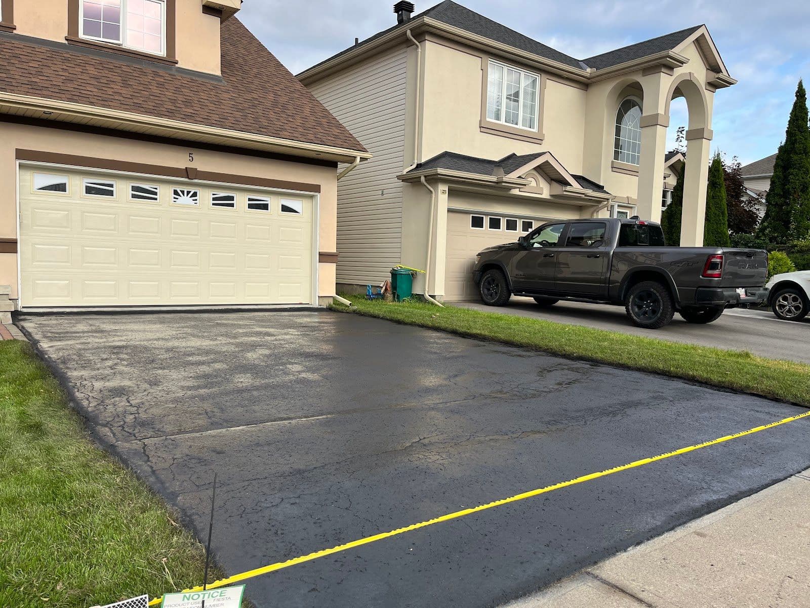 Asphalt sealing crew reviewing customer feedback on a tablet beside their work truck after completing a driveway job