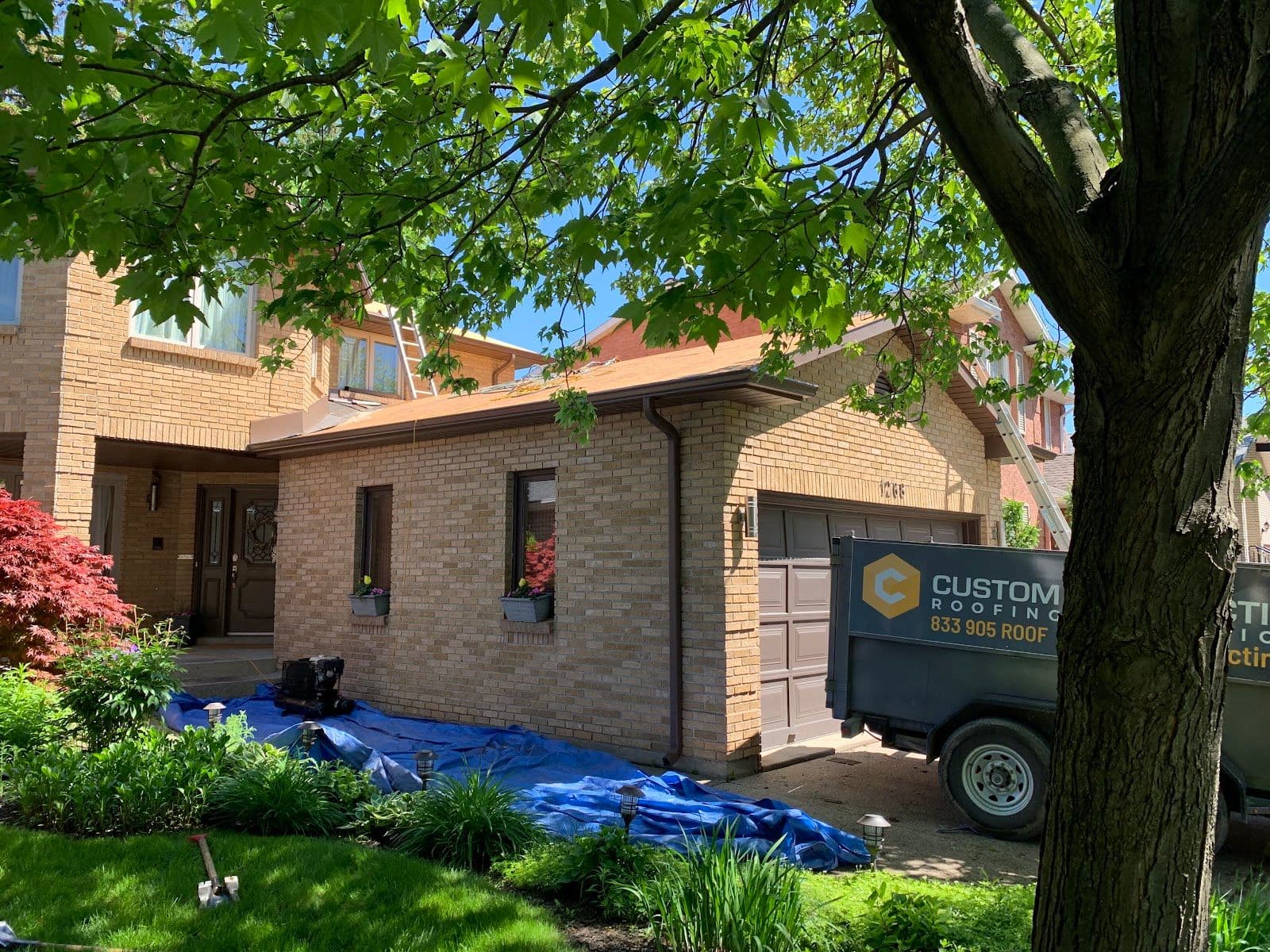 A roofing contractor and office manager reviewing customer feedback together on a tablet while sitting in a work van outside a residential home