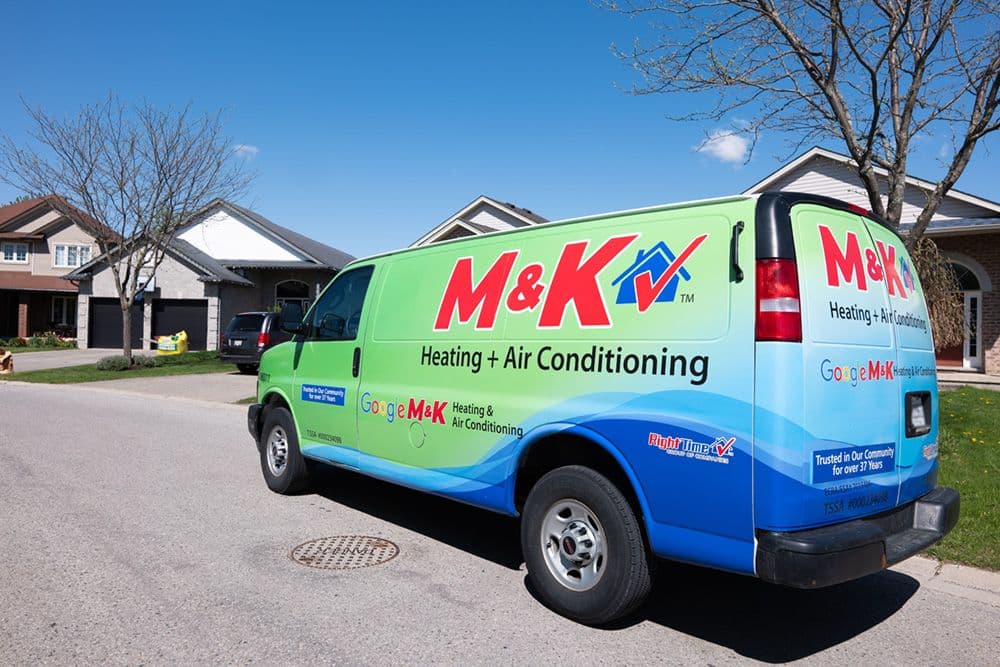 Two HVAC technicians in a service van reviewing customer feedback and job notes on a tablet before heading to the next call