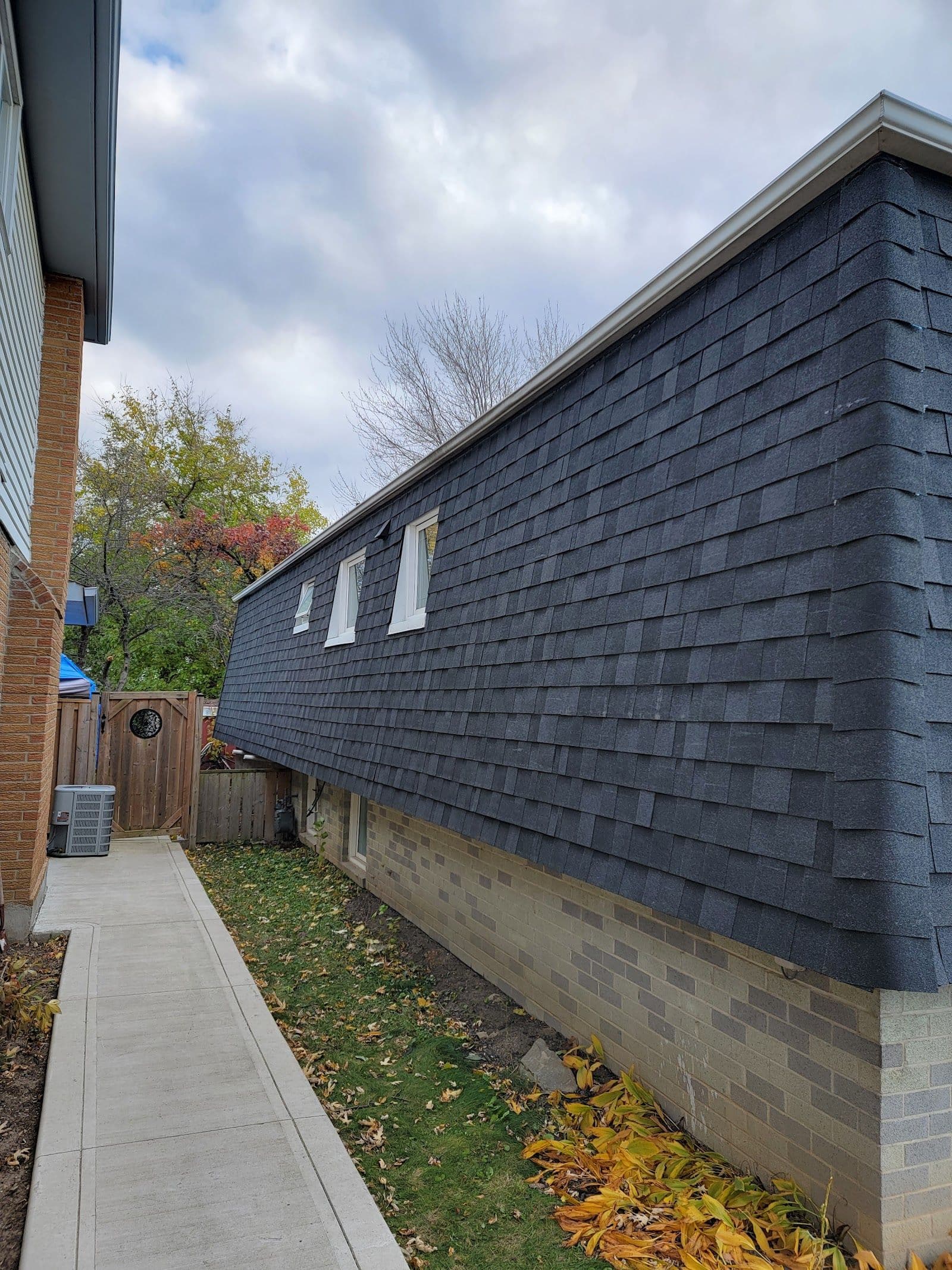 A roofing contractor and office manager reviewing customer feedback together on a tablet while sitting in a work van outside a home in Kitchener-Waterloo
